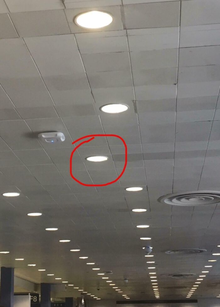 Unfortunate public interior design with misaligned ceiling light and tiles, creating a noticeable visual flaw.