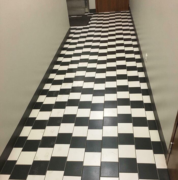 Black and white tiled floor in a narrow hallway, showcasing unfortunate interior design choices.