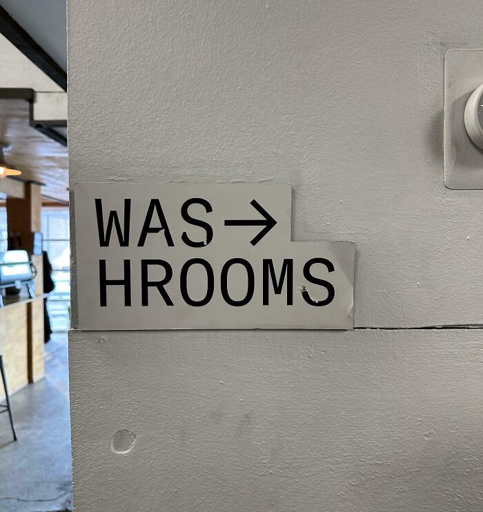 Sign reading "WAS HROOMS" in a public interior, highlighting unfortunate design.