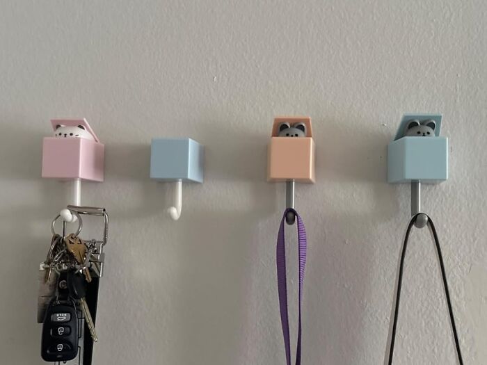 Cute animal wall hooks in pastel colors holding keys and straps; example of dopamine decor accessories.