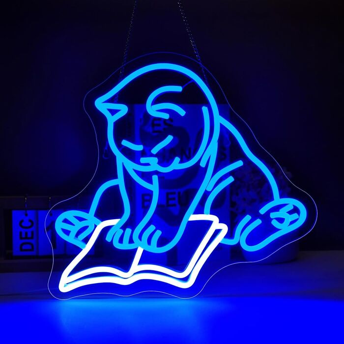 Neon cat reading a book, part of dopamine decor for vibrant interiors.