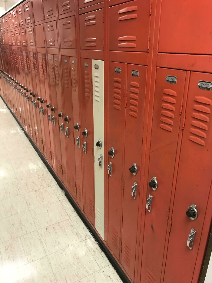 Row of red lockers with one mismatched white door, showcasing unfortunate interior design.