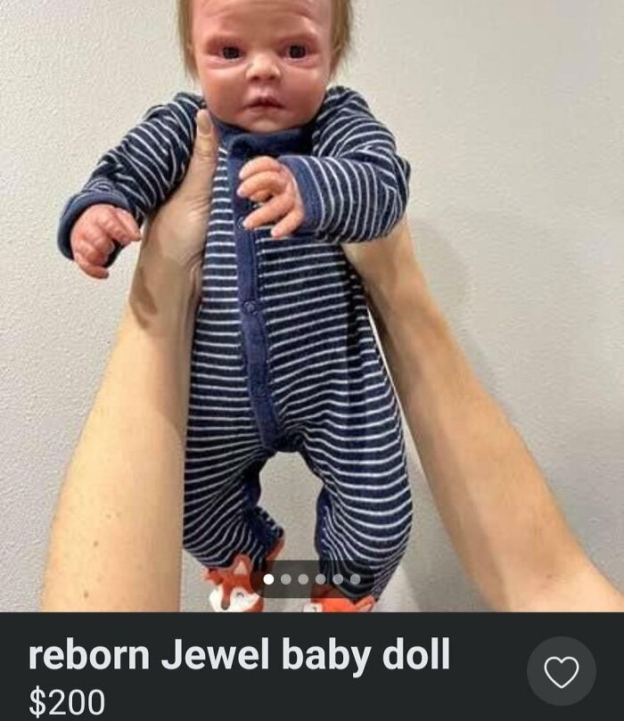 Reborn Jewel baby doll in striped outfit held up. Creepy things to sell online.