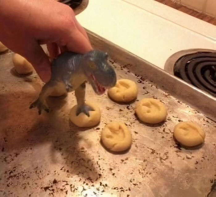 A toy dinosaur making foot imprints on cookie dough, creating a humorous science meme.