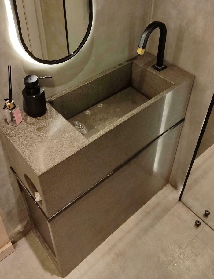 A narrow bathroom sink with a high curved faucet, showcasing unfortunate interior design.