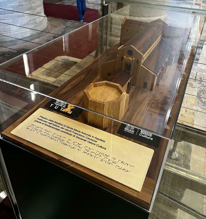 Scale model in a glass display, featuring public interior design, with an informational plaque in front.