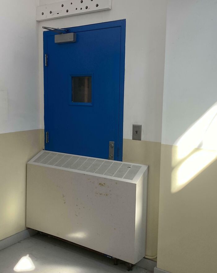 Unfortunate interior design with a blue door partially blocked by a radiator in a hallway.