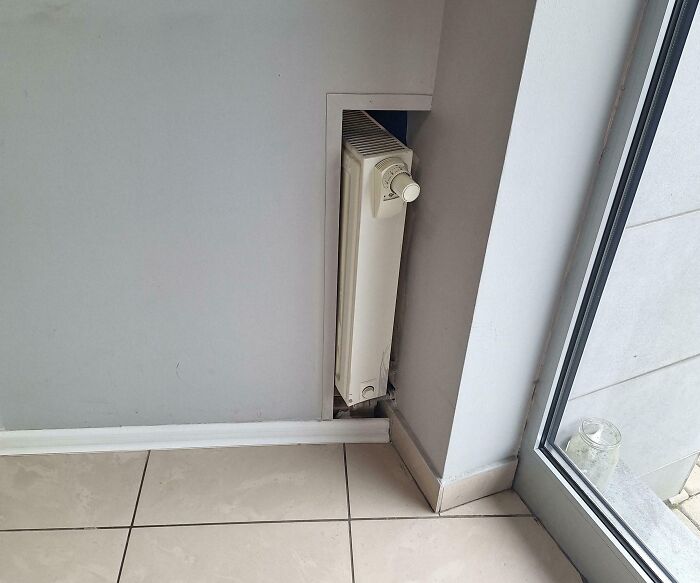 Radiator awkwardly built into a wall corner, showcasing unfortunate public interior designs.