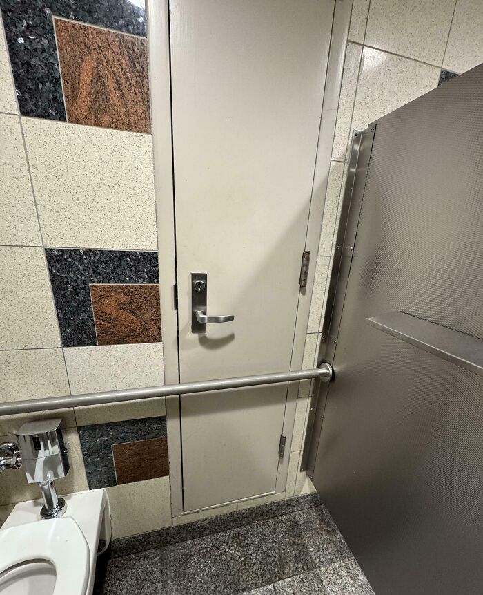 Restroom with unfortunate interior design, door obstructed by toilet and handrail, highlighting design flaw.