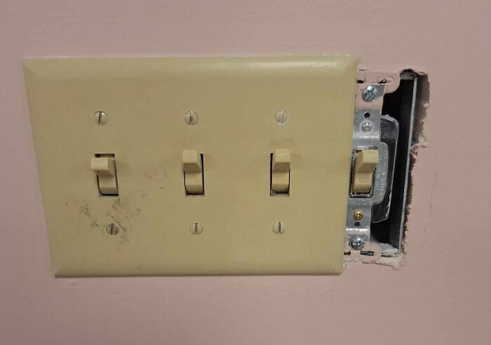 Unfortunate public interior design with a misaligned light switch plate revealing wall gap.