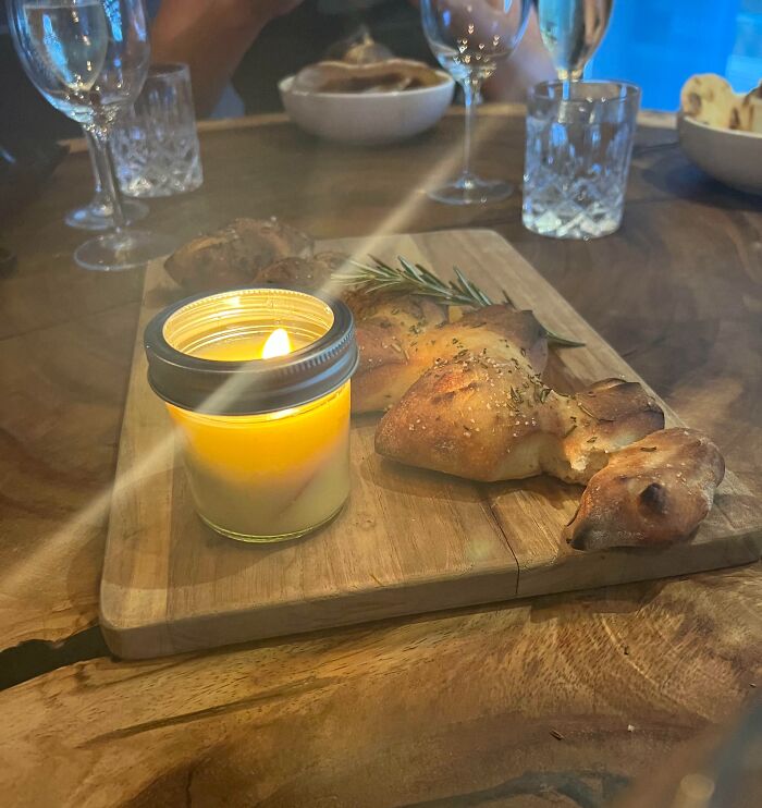 A lit candle beside freshly baked bread on a wooden board, showcasing cool products with surprises.