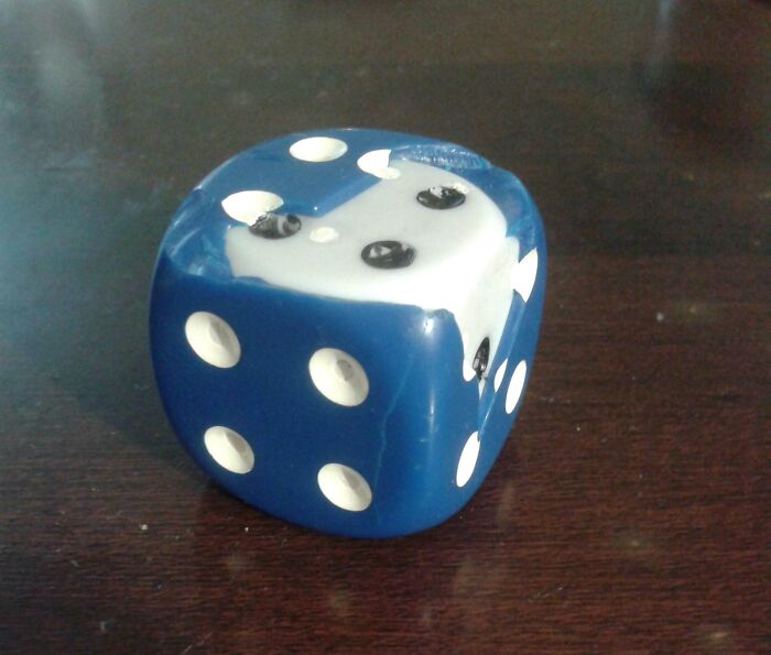 Blue dice with broken corner revealing a white interior, exemplifying cool products with surprises.