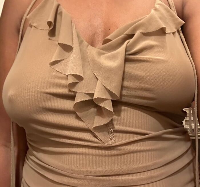 A close-up of a beige ruffled dress fitting tightly, illustrating unavoidable body issues.