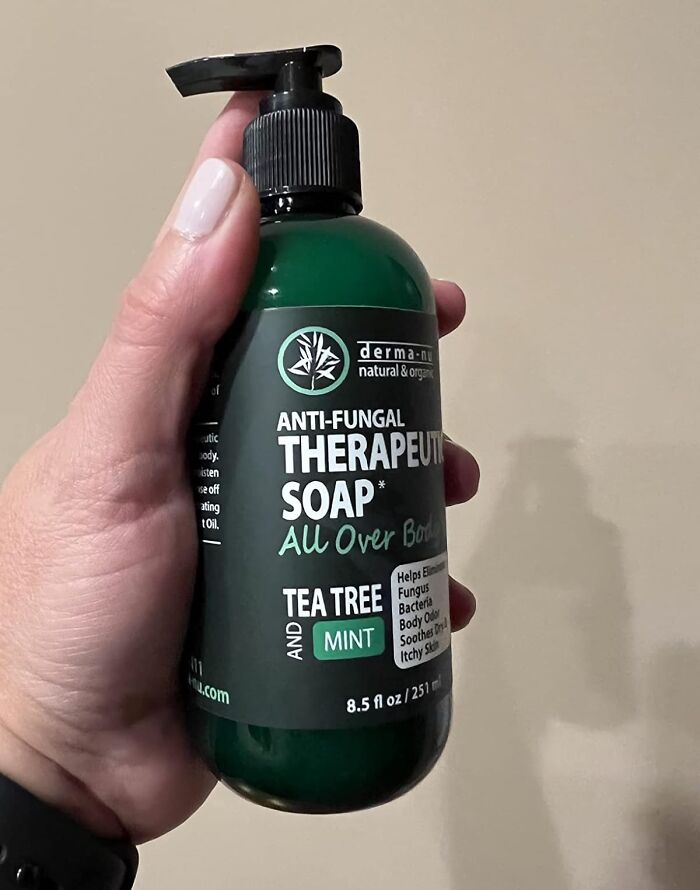 Hand holding anti-fungal body soap with tea tree mint for unavoidable skin issues.