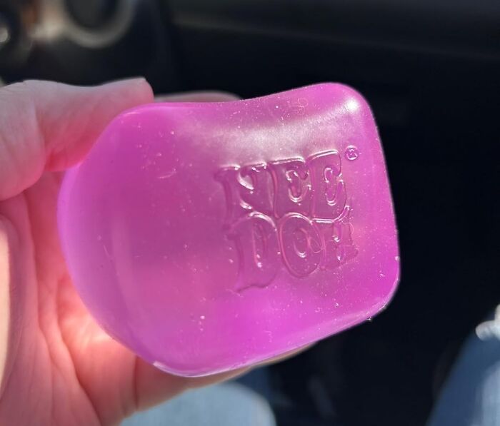 Hand holding a purple "#TikTokMadeMeBuyIt" bar soap with embossed text in bright light.