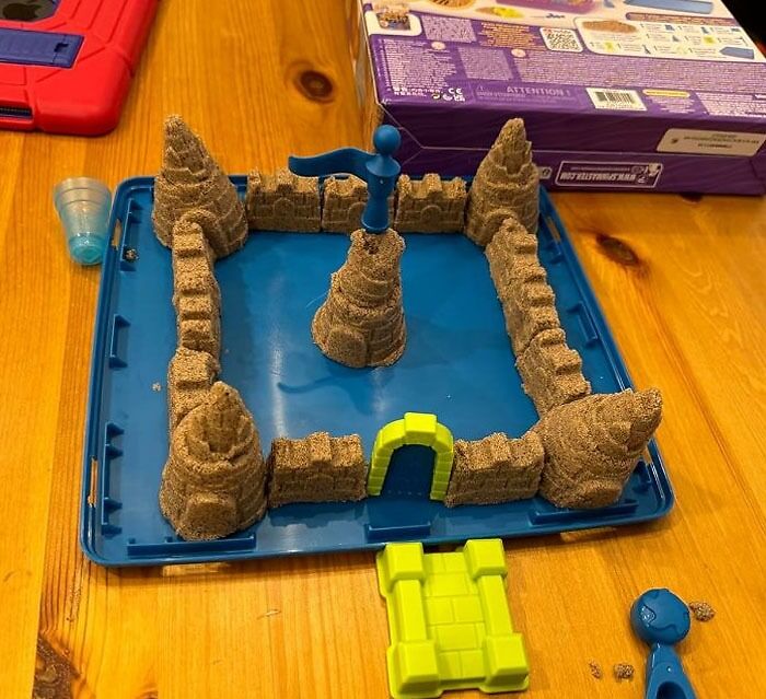 Kinetic sand castle kit setup on a table, a popular TikTokMadeMeBuyIt item with creative molds and vibrant colors.