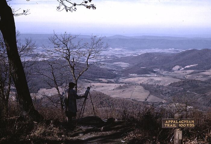 Person painting a scenic view of the Appalachian Trail, with rolling hills in the background, captured in 1940 color photos.