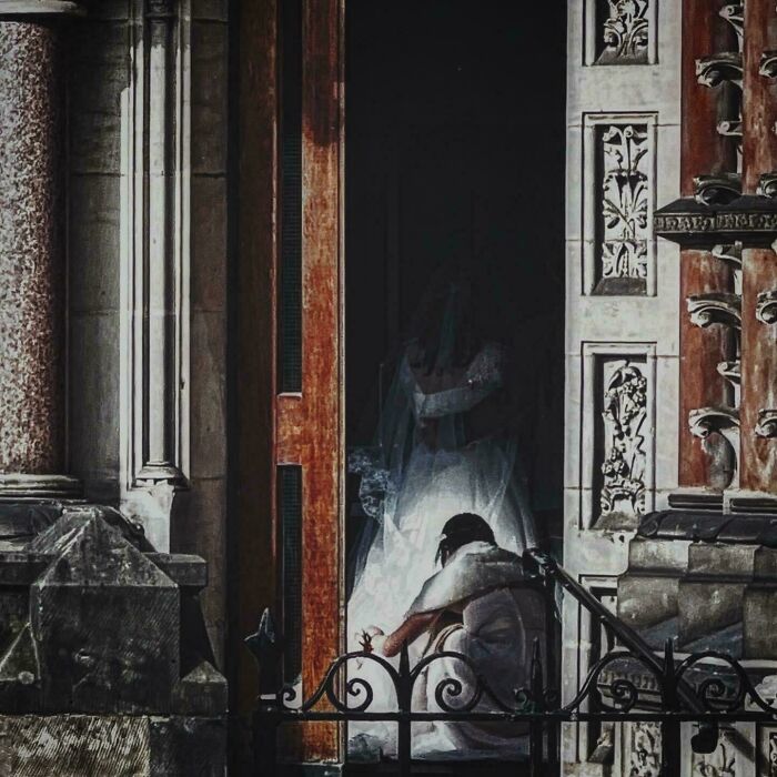 A person kneeling before a bride, in a setting reminiscent of Renaissance paintings, with ornate architectural details.