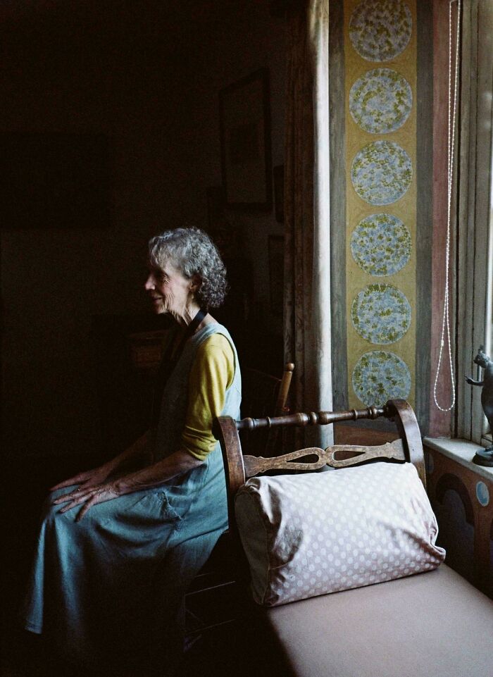 A woman sitting by a window, resembling a detailed scene from a Renaissance painting.