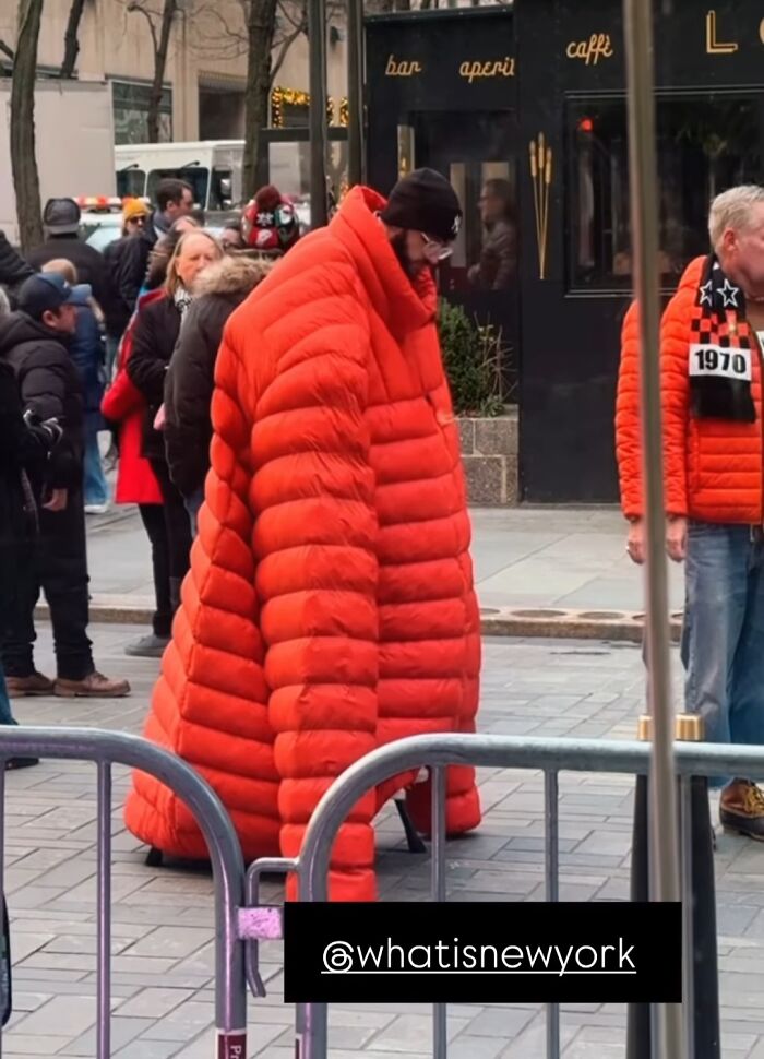 NYC local wearing an oversized red puffer jacket, showcasing unique fashion in a busy New York street setting.