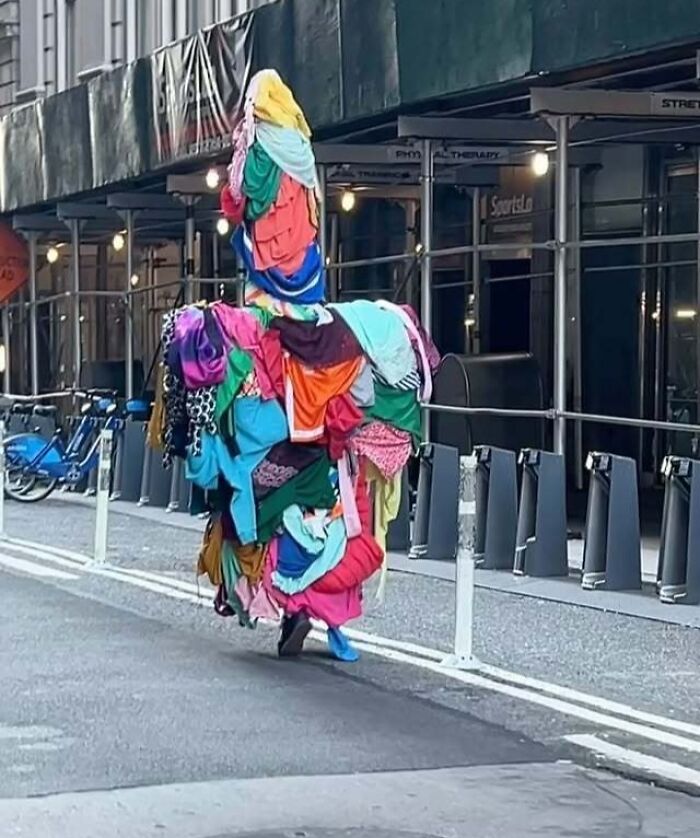 A NYC local walking down the street, boldly experimenting with fashion by wearing a vibrant pile of assorted clothes.