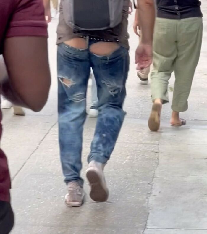 NYC local wearing creatively torn jeans while walking on a city street, showcasing unique fashion experimentation.