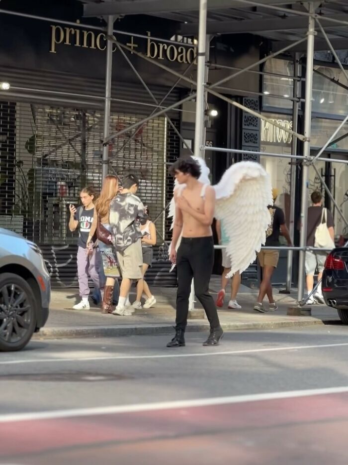 NYC local showcases bold fashion with angel wings on a street, exemplifying experimental style.