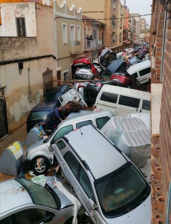 Cars piled up on a narrow street after severe flooding, highlighting nature disaster resilience challenges.