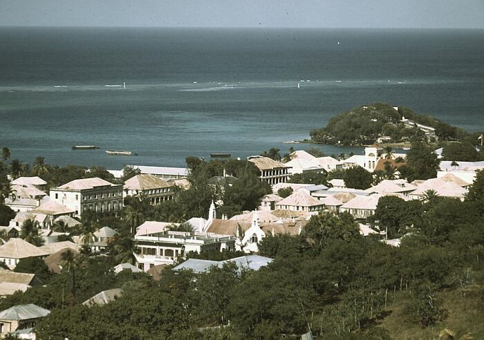 1940 color photos of a coastal village with white buildings and lush greenery by the ocean.