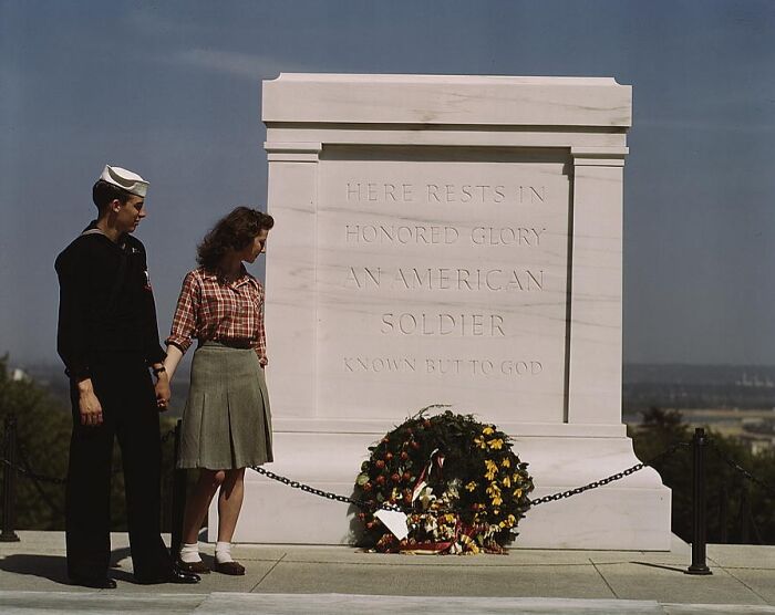 1940 color photo of a sailor and woman at the Tomb of the Unknown Soldier, with a wreath placed in honor.