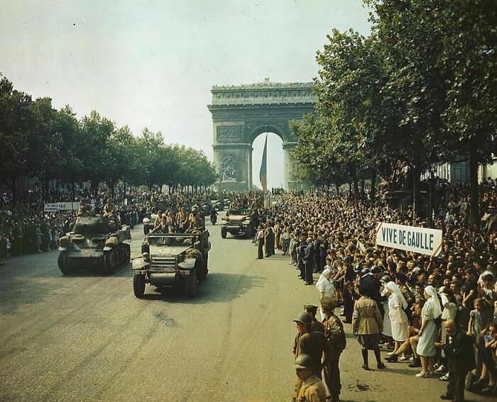 1940 color photos of a military parade with tanks and cheering crowds near the Arc de Triomphe, Paris.