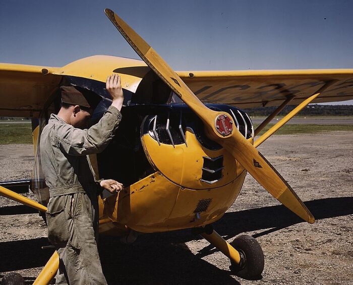 Man in military uniform inspecting a yellow airplane, 1940 color photos.