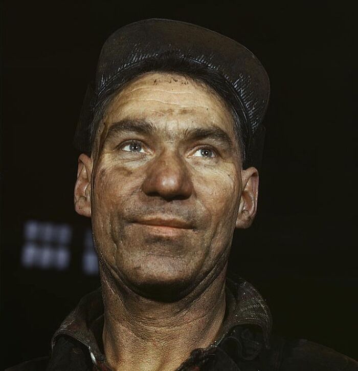 Man with a dirty face and a cap in a 1940 color photo portrait.