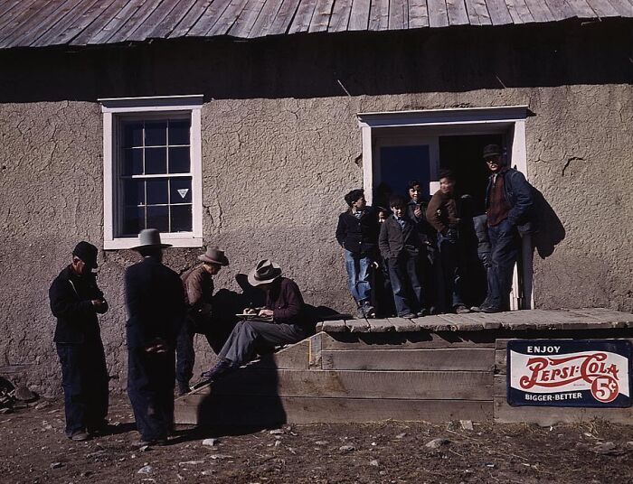 1940 color photo of men and boys outside a building with a vintage Pepsi-Cola sign.