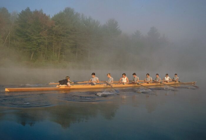 Rowers in a wooden boat on a misty lake, surrounded by trees, illustrating 1940 color photos.