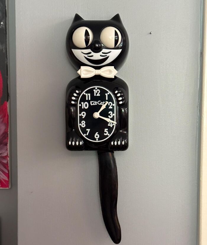 Retro Fever: Classic black Kit-Cat clock with swinging tail and rolling eyes against a gray wall.