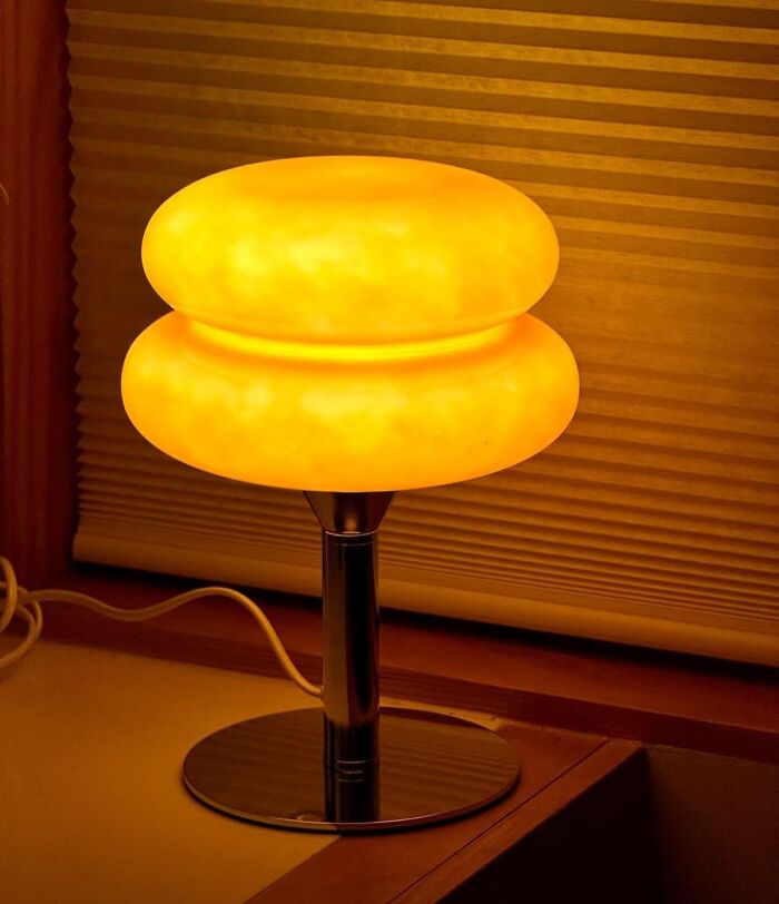 Retro lamp with a glowing orange shade on a wooden surface, creating a vintage ambiance.