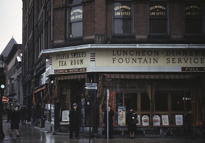 Street scene with pedestrians in front of Sylvia Sweets Tea Room in a 1940 color photo.