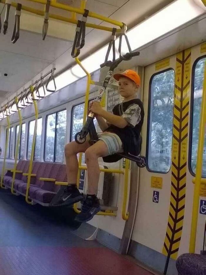 Young passenger amusingly hangs on a subway train while sitting on a scooter, showcasing funny train antics.