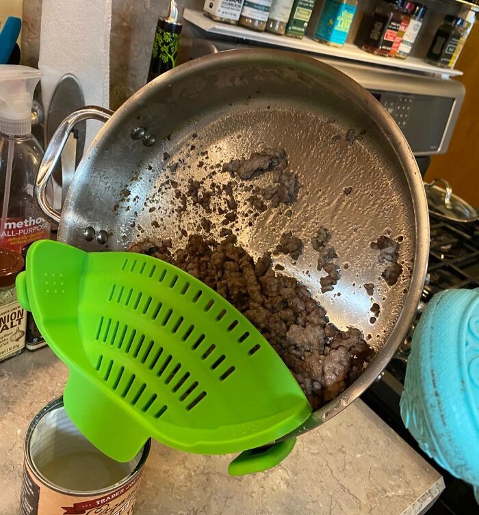 Green strainer clipped to a pot with cooked ground beef, popular every home find in a kitchen setting.