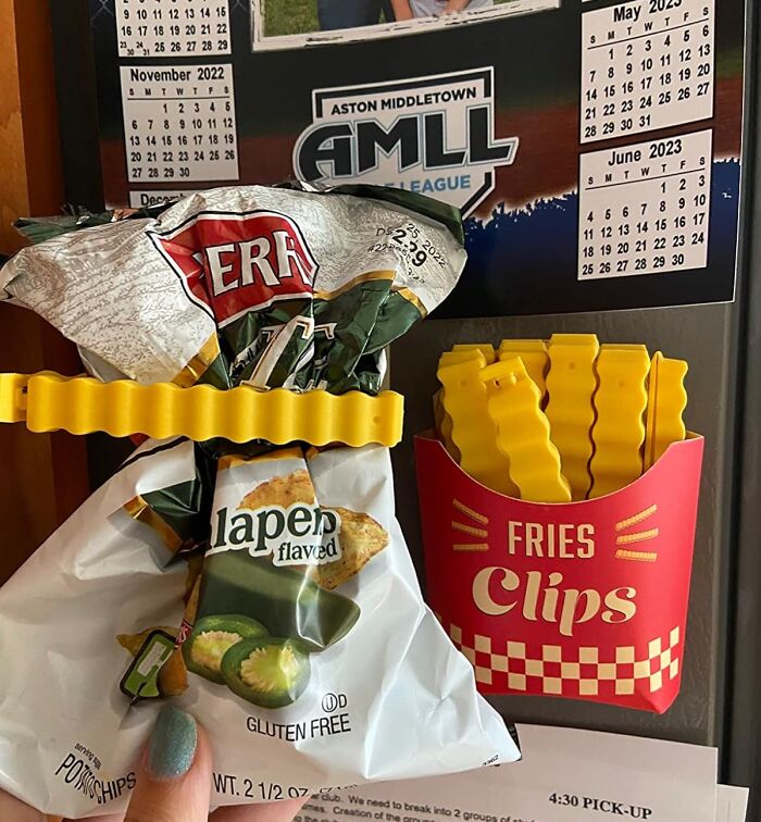 Fries-shaped clips sealing a bag of chips on a fridge door with calendar.