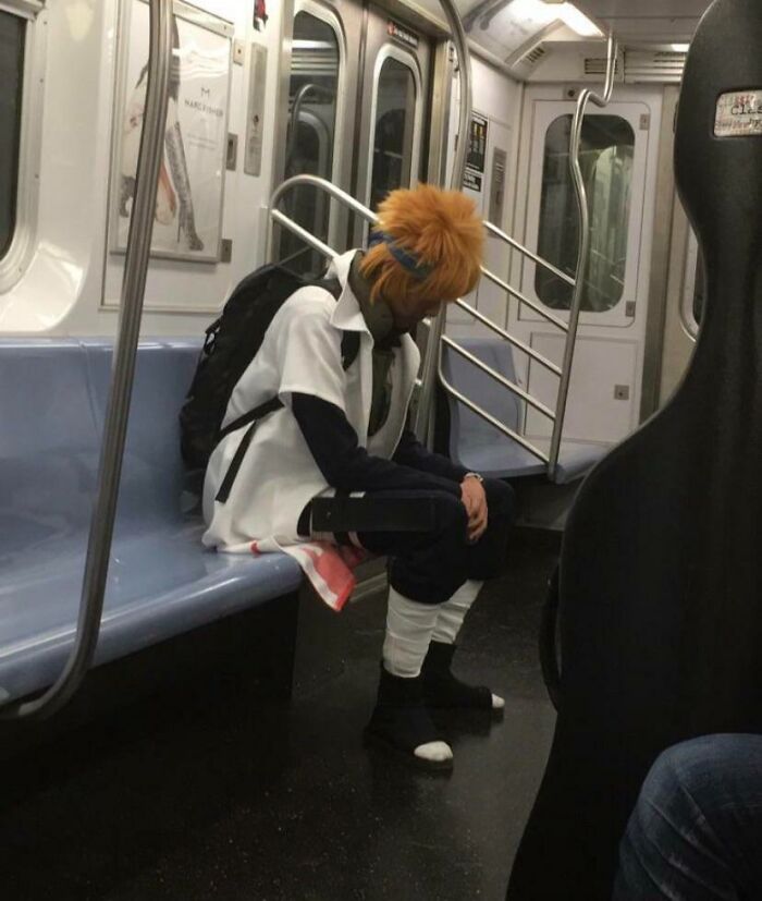 Subway passenger in funny costume with spiky hair and backpack on empty train.