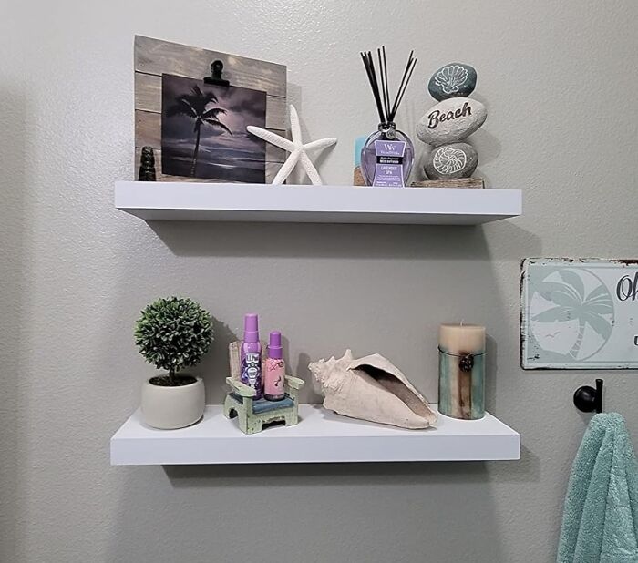 Bathroom shelves with decor items and new products, featuring a small plant, candles, and photo frame.