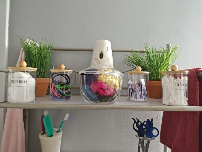 Bathroom shelf with jars of cotton balls, hair ties, and decor, showcasing highly-rated bathroom products.