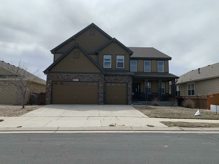 A large dark brown house under a cloudy sky, a setting for true crime stories and curiosities.