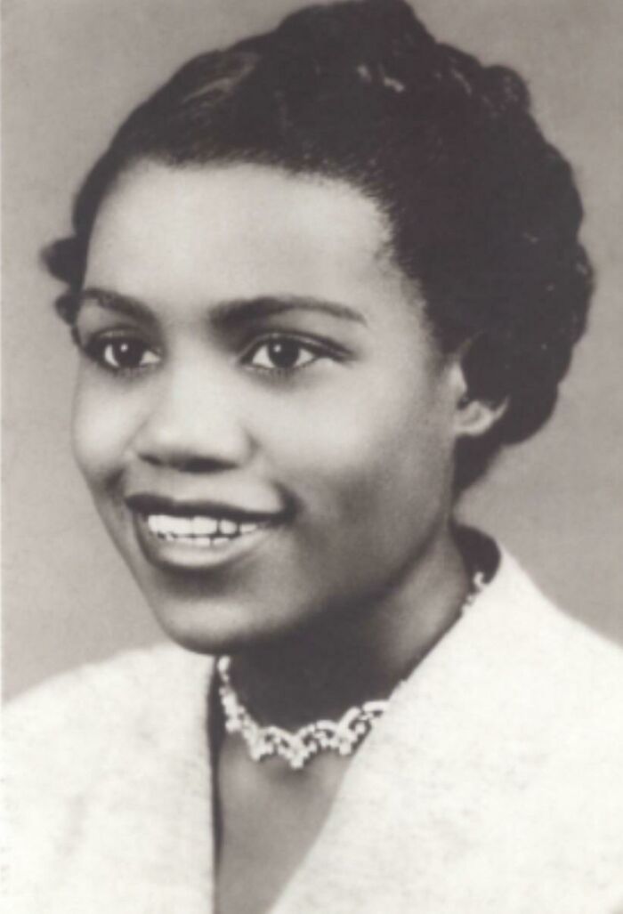 Portrait of a woman from a true crime story, wearing a light-colored top and a necklace, smiling softly.