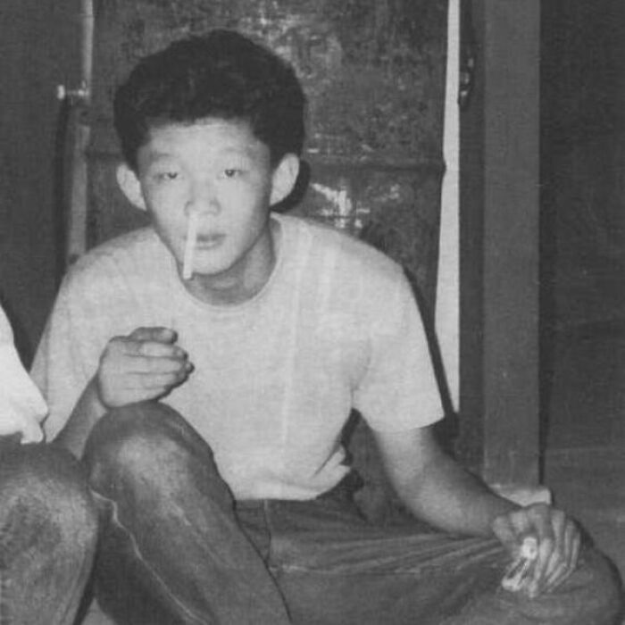 Young man sitting indoors, holding a cigarette, with another cigarette sticking out of his nose, representing crime curiosities.