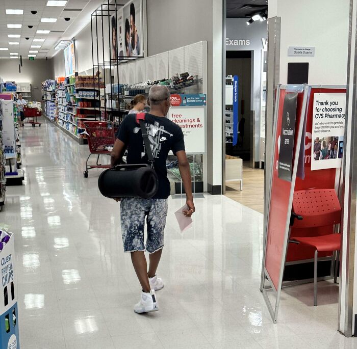 Person blocking aisle with a large speaker in a store, displaying inconsiderate behavior.