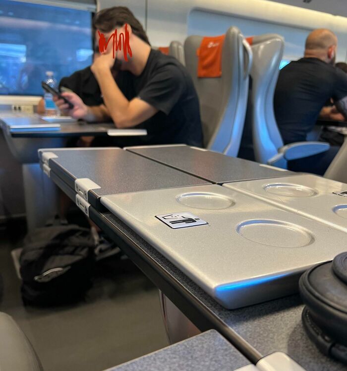 Train passenger with feet on the tray table, holding a phone, demonstrating people being complete jerks.