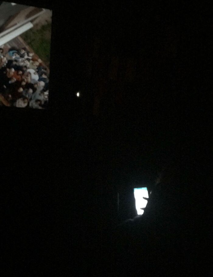 Person on phone in dark theater, disrupting others, showcasing people being complete jerks.